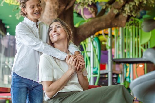 Niño abrazando a su mamá en un área de juegos